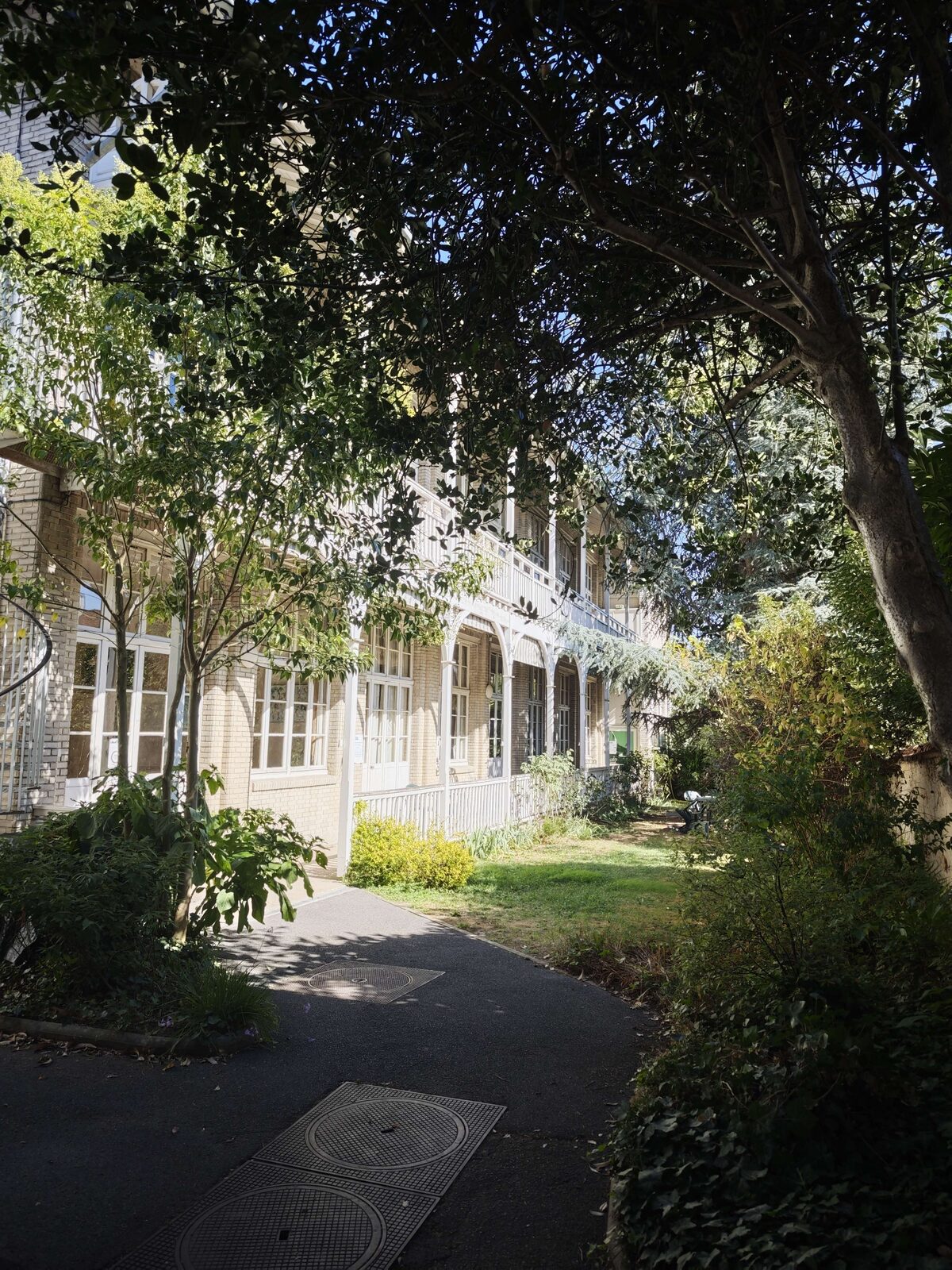 Façade du bâtiment du club d'échecs, avec sa galerie blanche en bois à l'étage, vue depuis le jardin